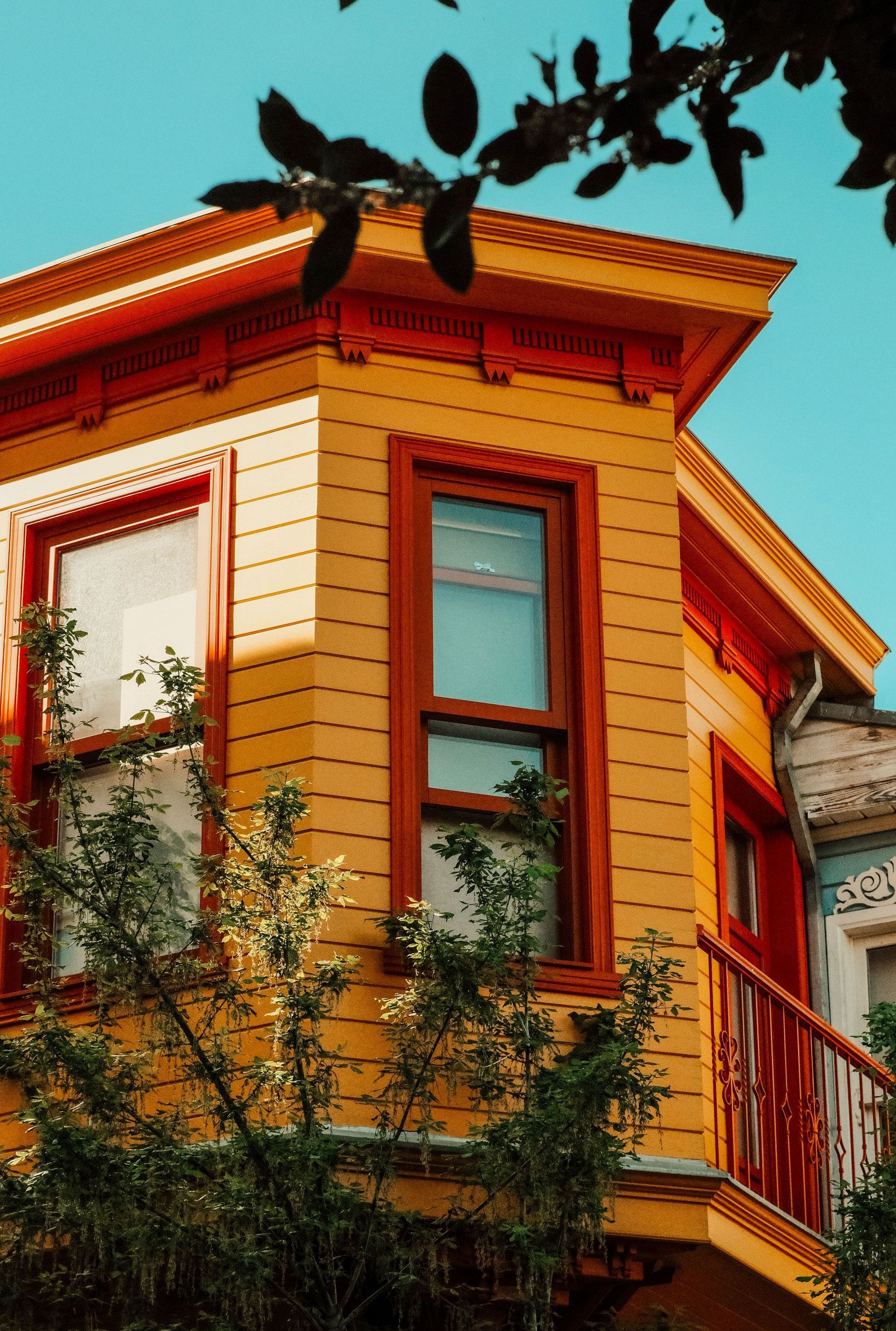 Colorful residential building facade with vibrant yellow paint and balcony, set against a clear sky in İstanbul.